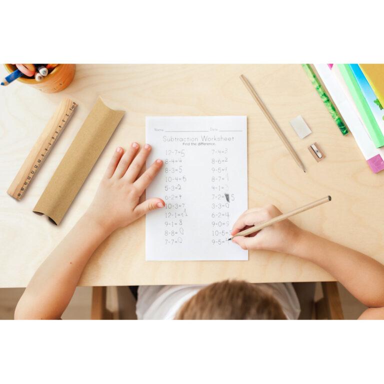 Top view of child hands with pencils. Solving maths exercises. 7 years old child doing maths lessons sitting at desk in his room.